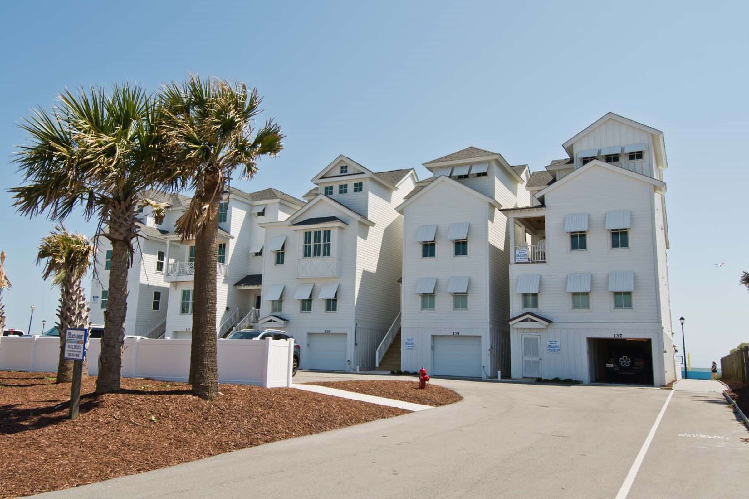 a white apartment complex with trees and a driveway